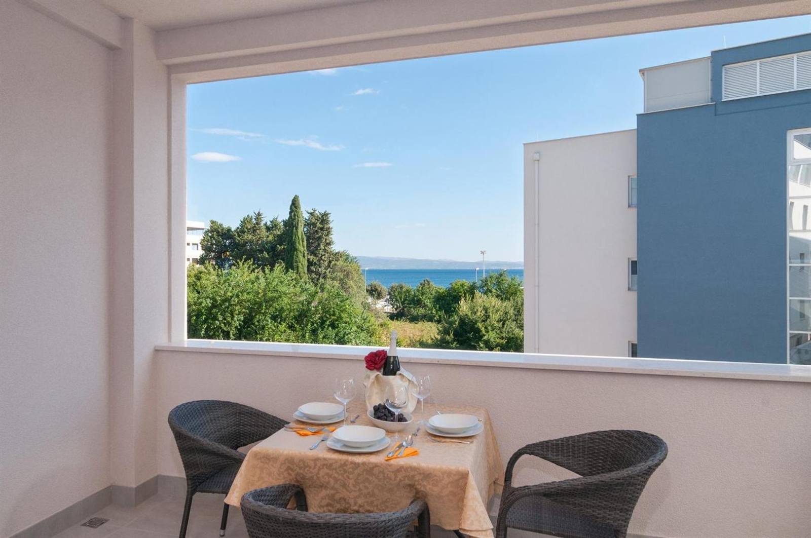 Table set for two on the balcony, with a large window and a sea glimpse