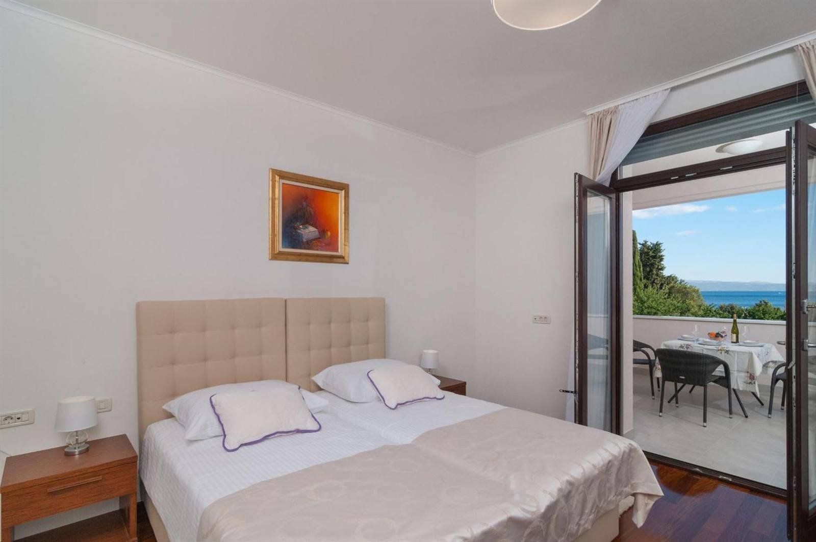 Twin beds with a balcony and a table with chairs outside